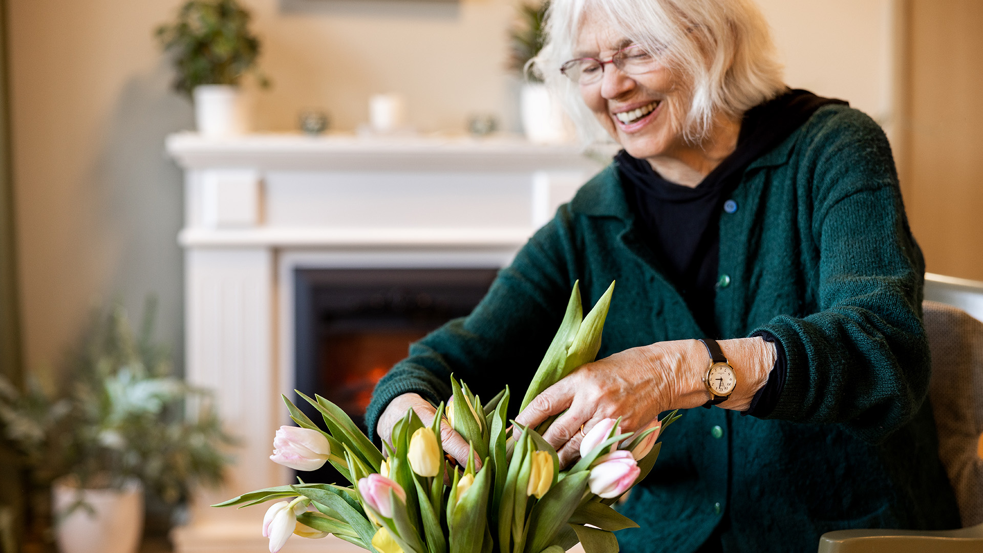 äldre kvinna arrangerar tulpaner i en vas