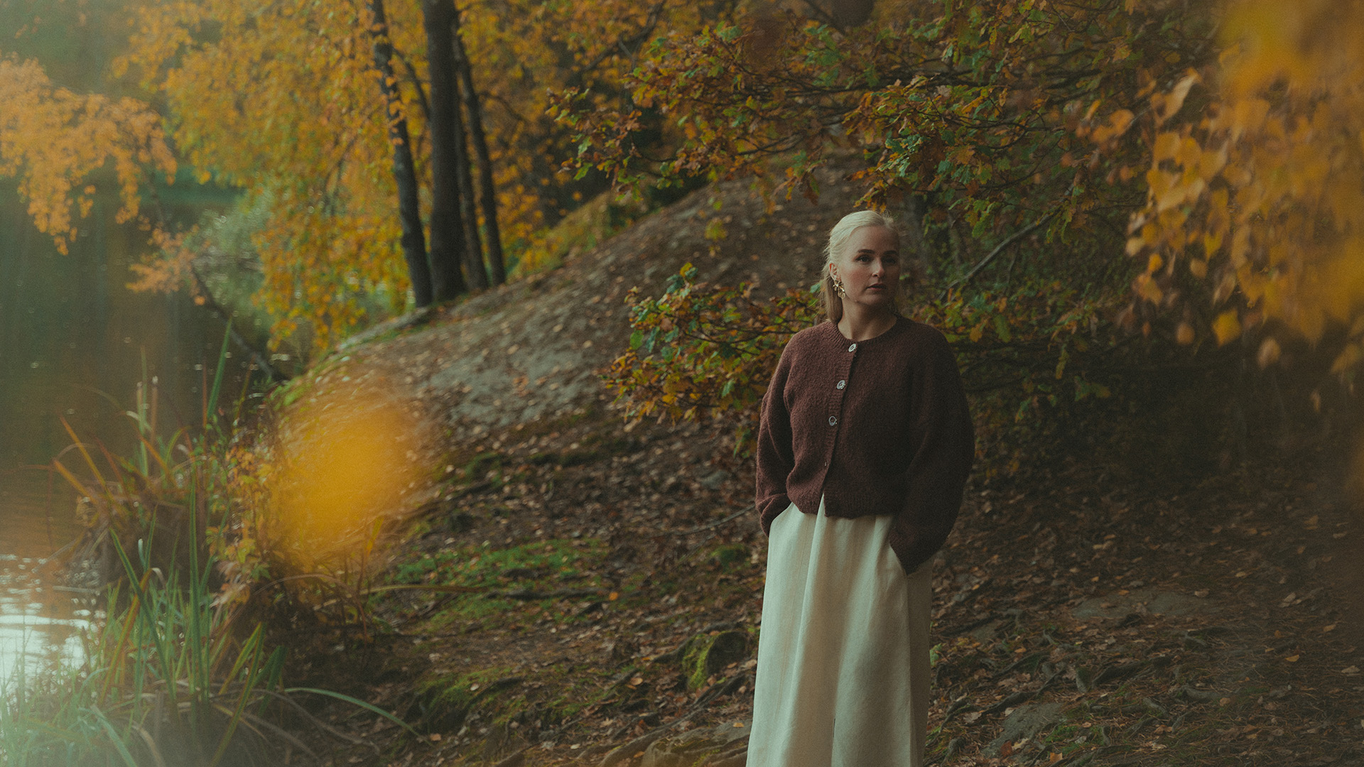 Portr&auml;tt av Lovisa Jennervall bland h&ouml;stl&ouml;v vid ett vattendrag