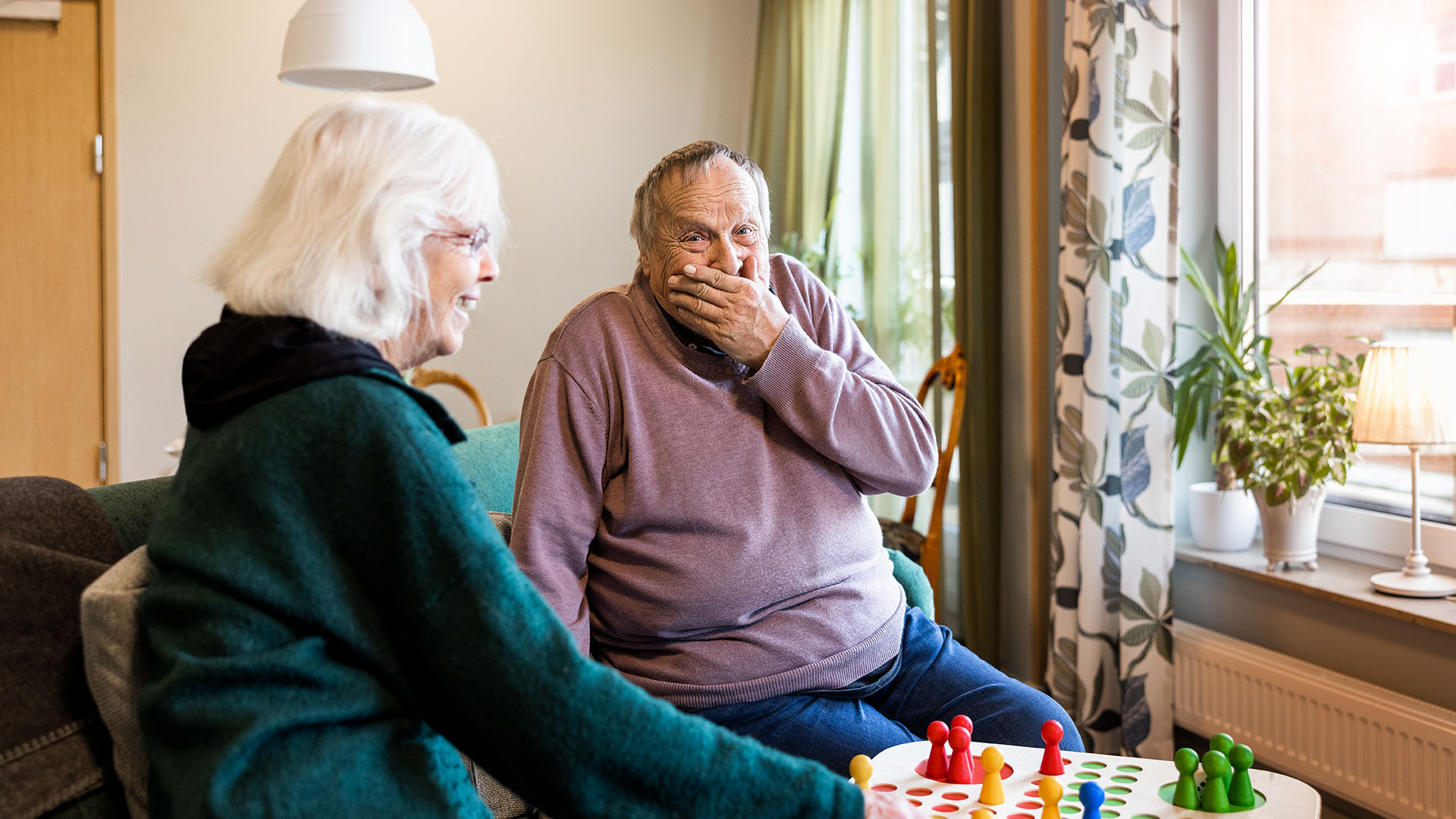 man och kvinna spelar fia, mannen lägger leende en hand för munnen