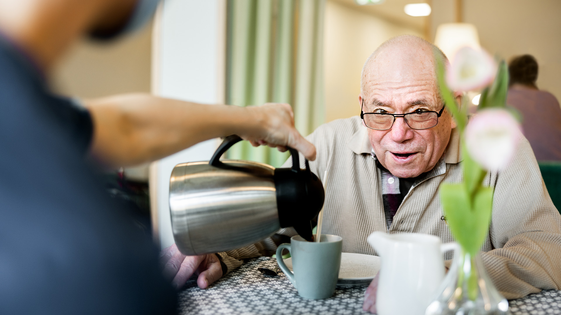 bild på en man som får sitt kaffe serverat av personalen på ett äldreboende