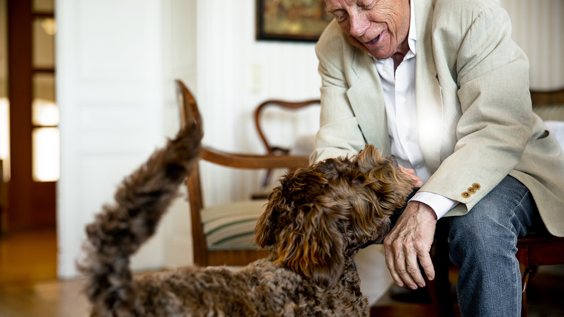 äldre man klappar en brun hund