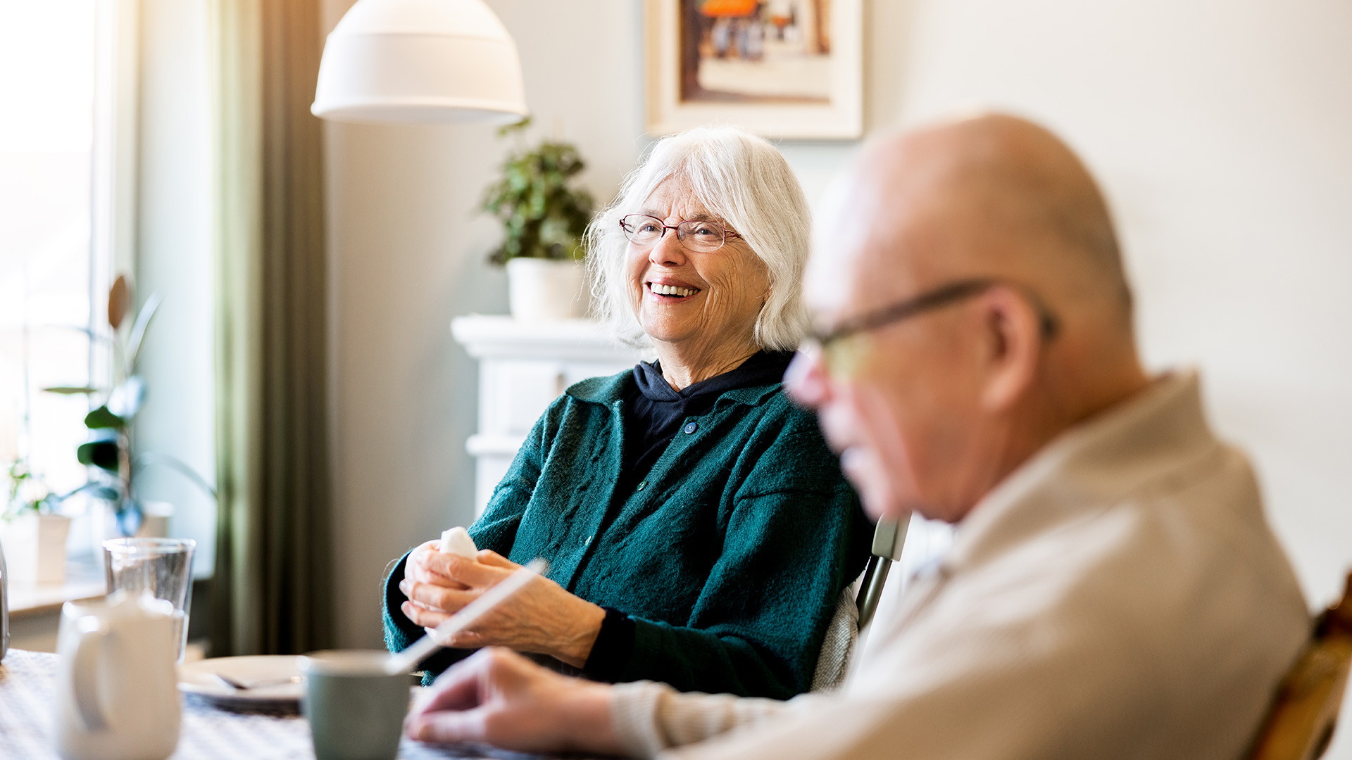 skrattande äldre kvinna sitter vid ett bord tillsammans med en äldre man