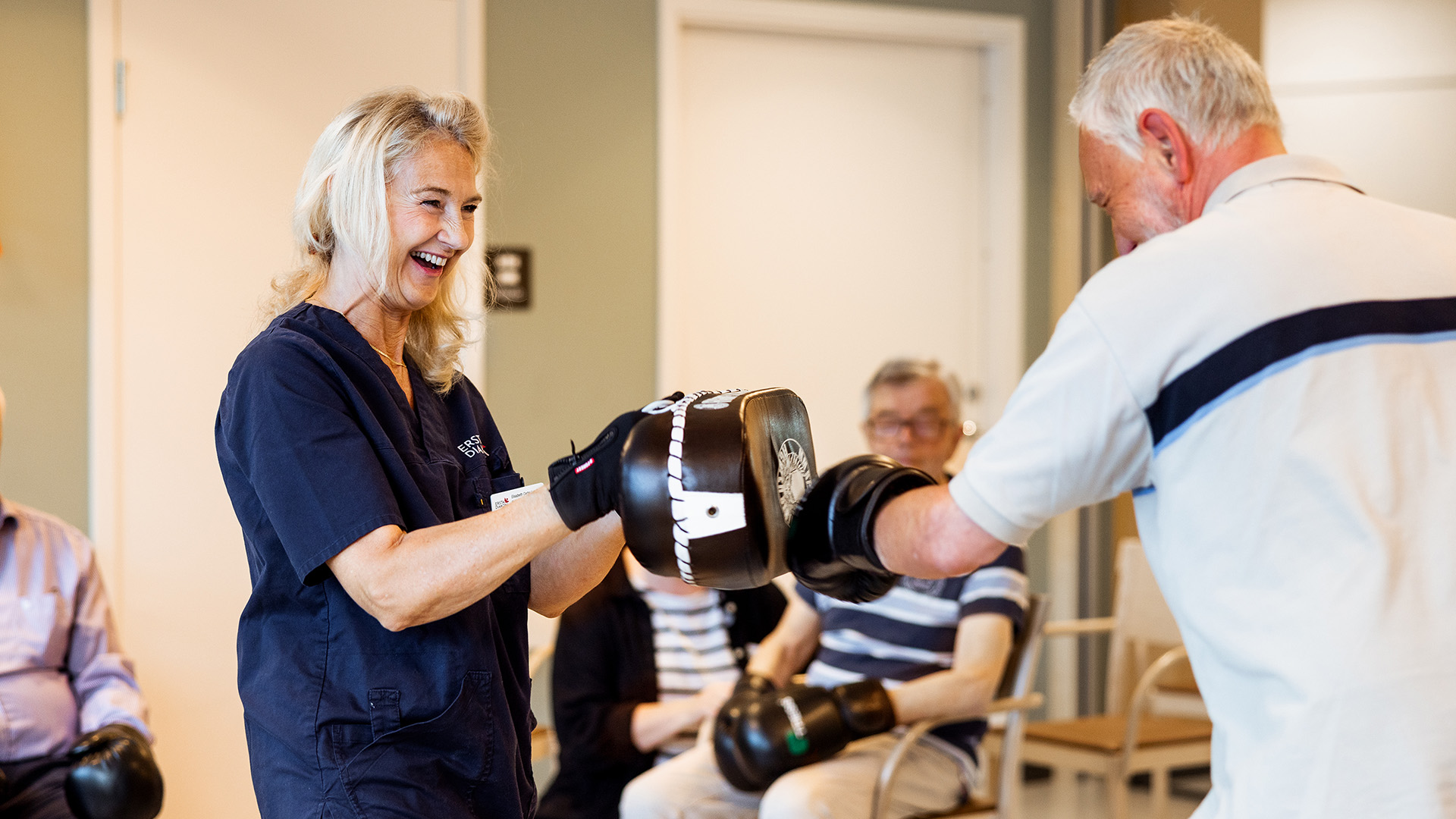 en anställd och en äldre man boxas med boxhandskar och skrattar