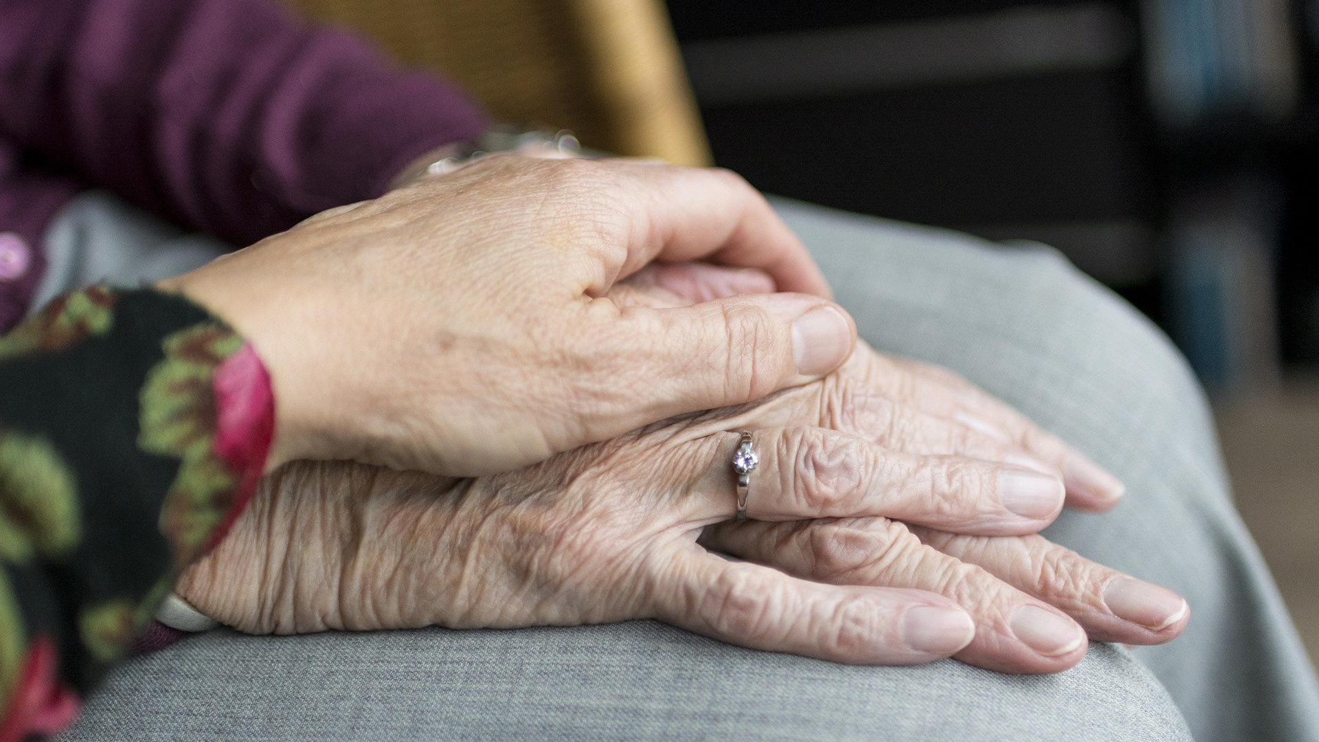 En person lägger sin hand över en äldre persons hand.