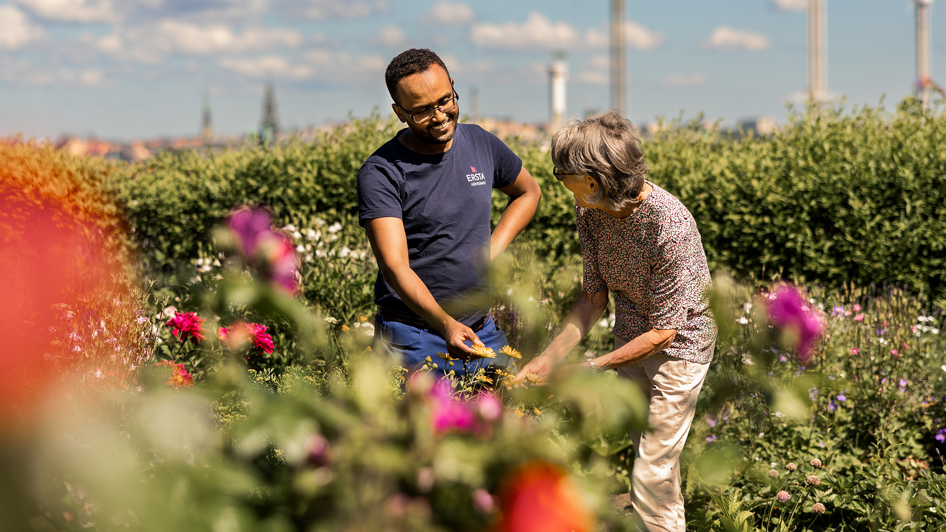 en kvinna och en hemtjänstmedarbetare står i en blommande park 