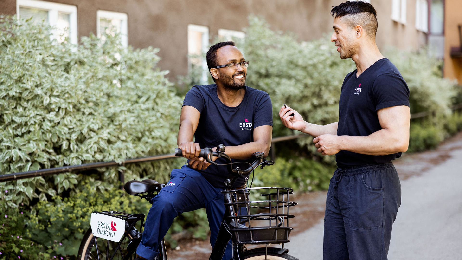 två merbetare från ersta hemtjänst står vid en cykel och pratar