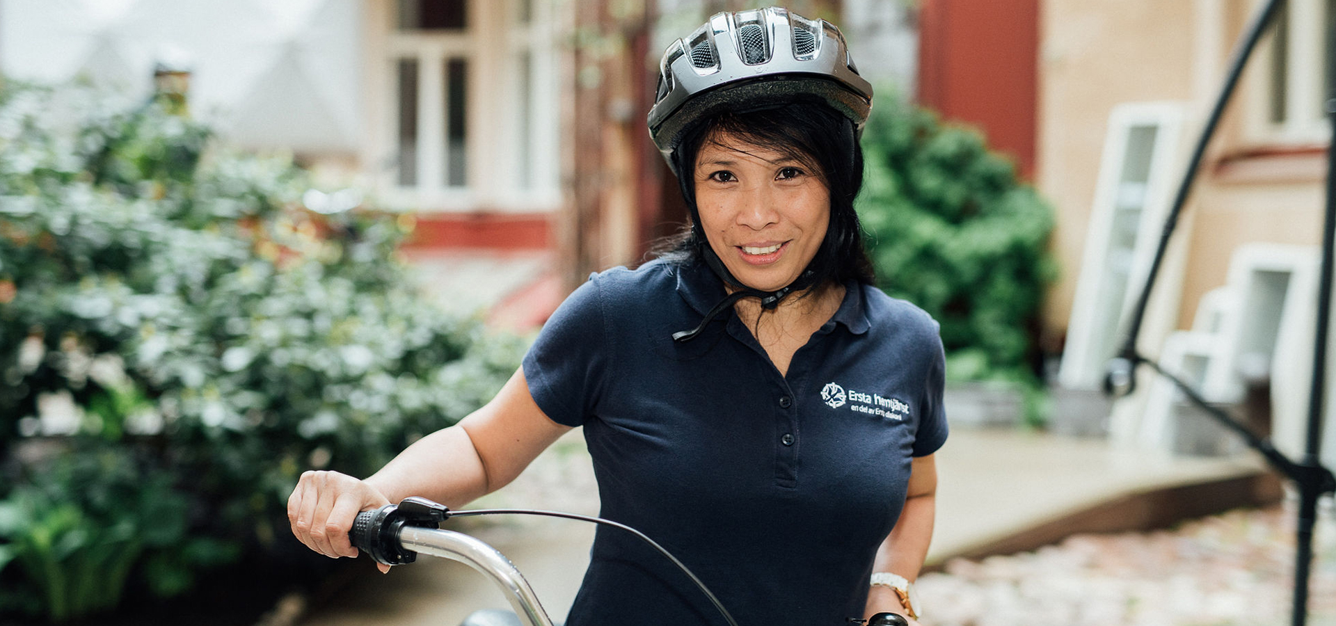 kvinna som jobbar inom ersta hgemtjänst står med cykel