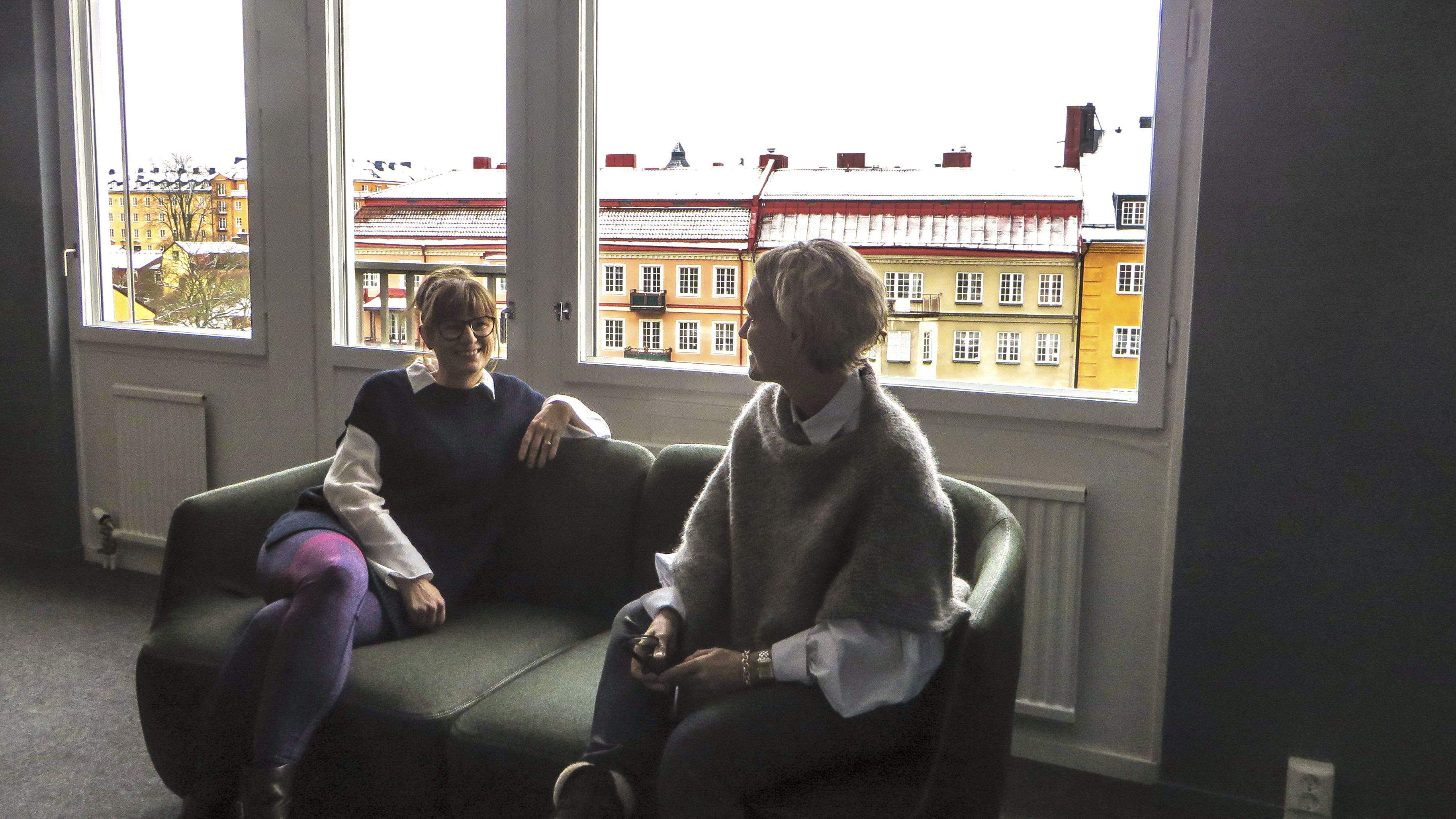Kvinnor sitter i soffa framför fönster med utsikt
