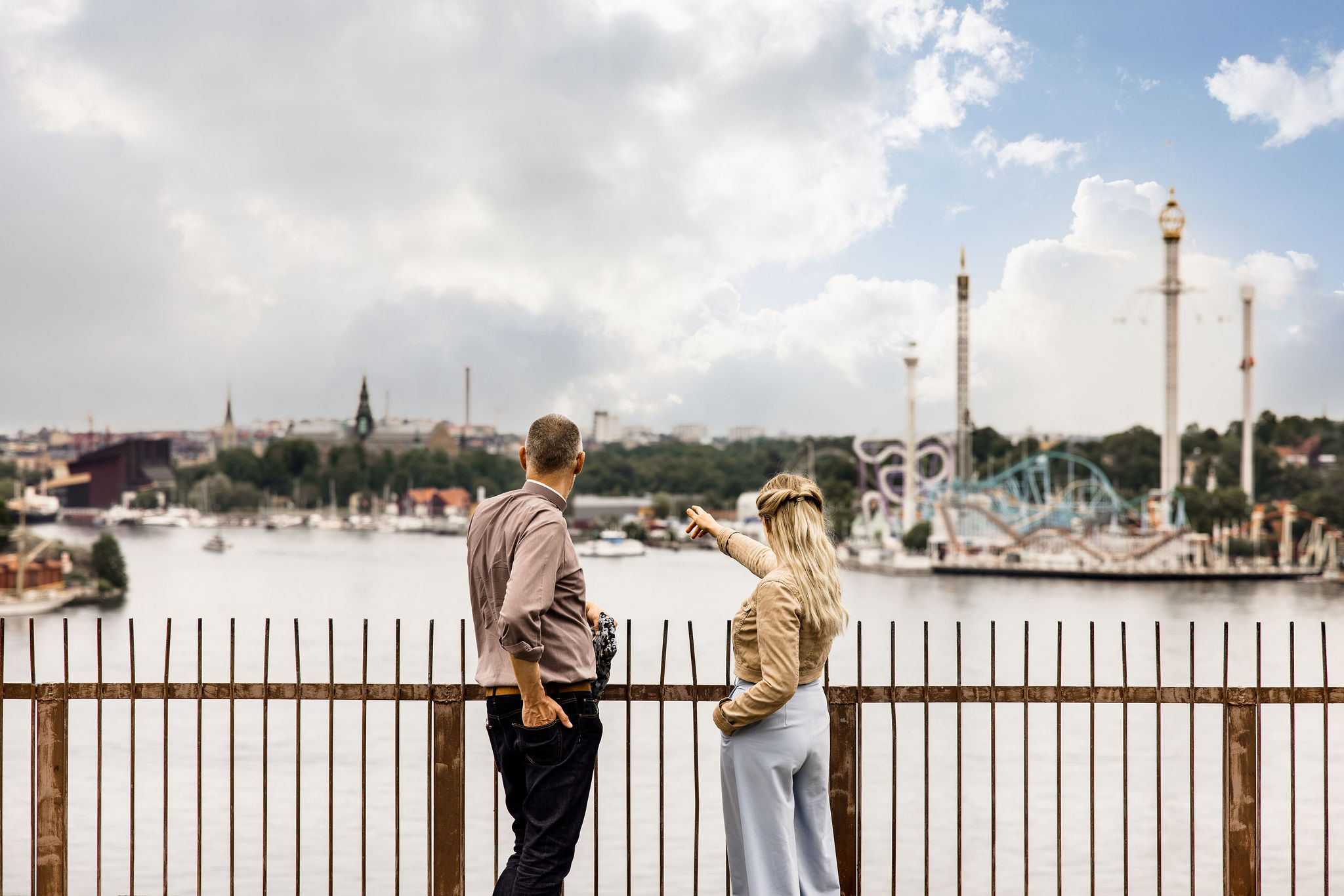 två personer beundrar utsikten på Erstaklippan, gröna lund skymtas i bakgrunden