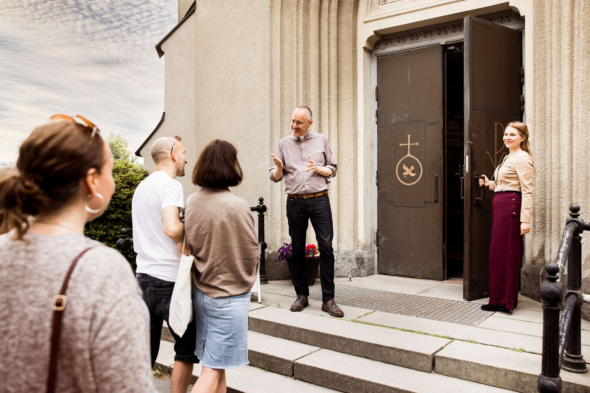präst och besökare vid ingången till kyrkan