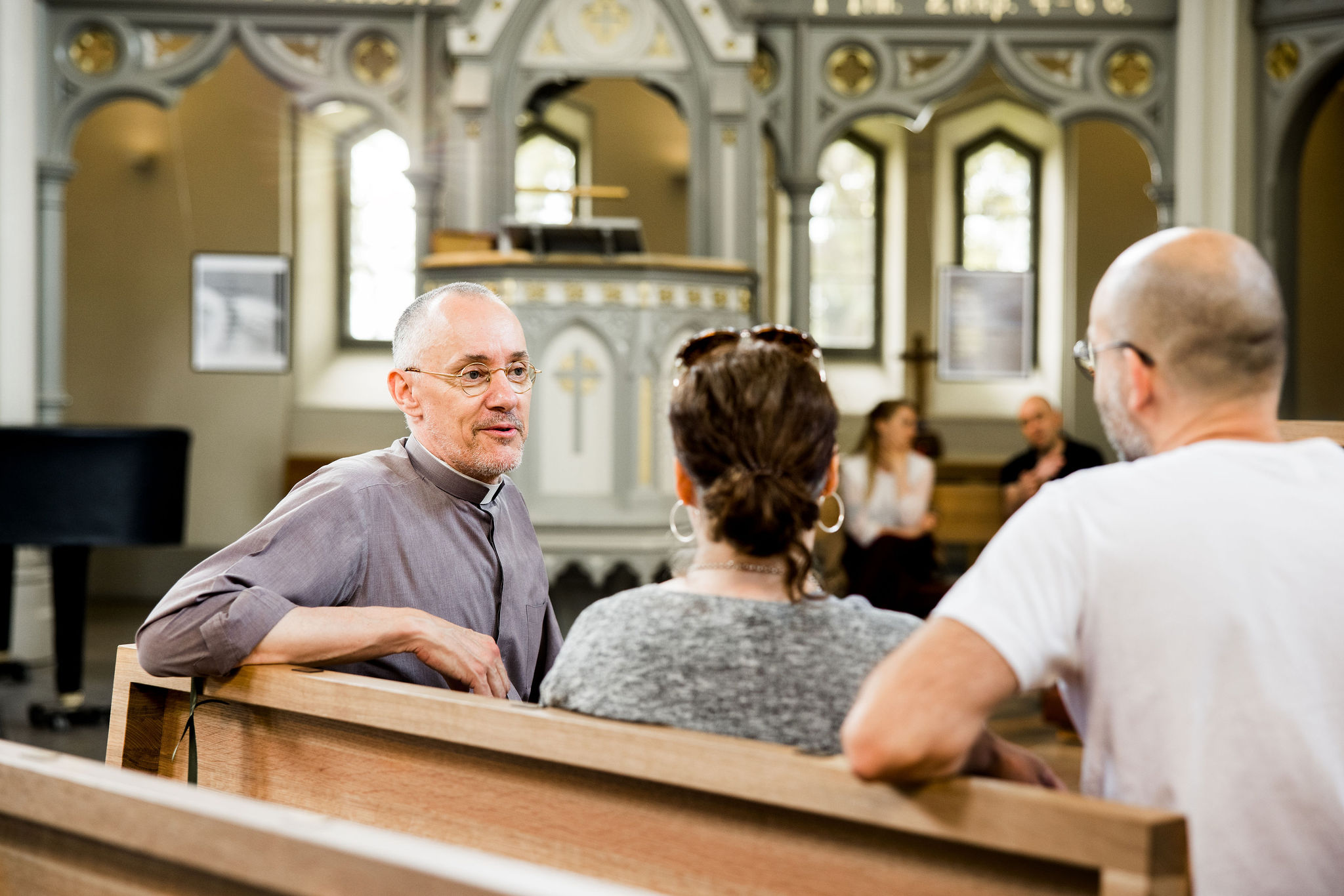 präst i samtal med besökare inuti kyrkan