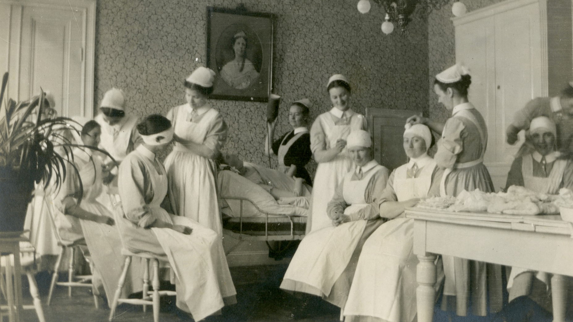 Historisk bild där sjuksyster ger kvinna i sjuksäng medicin