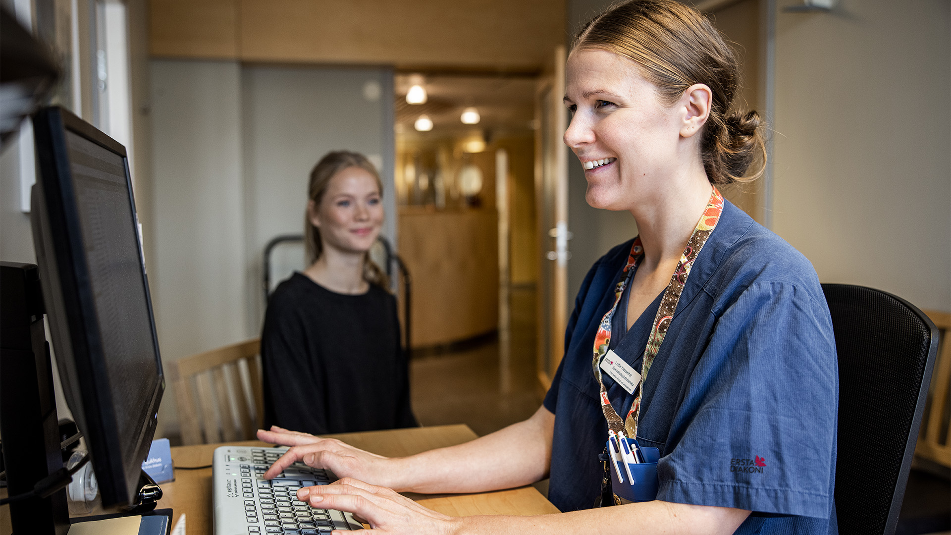 Medarbetare sitter vid datorn med en patient bredvid sig