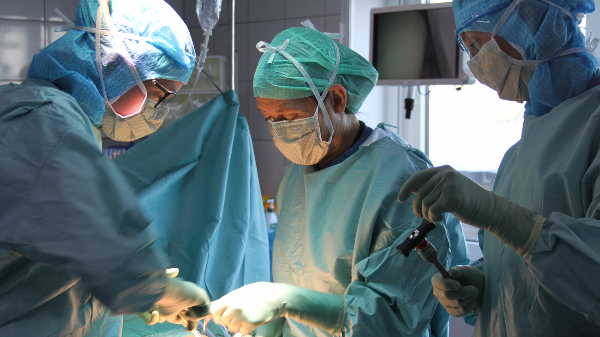 Bild från operation, kirurg assisterad av övrig operationspersonal